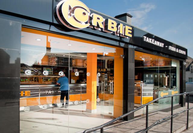 Granite and glass shopfront with illuminated signage at the Corbie fish and chip takeaway