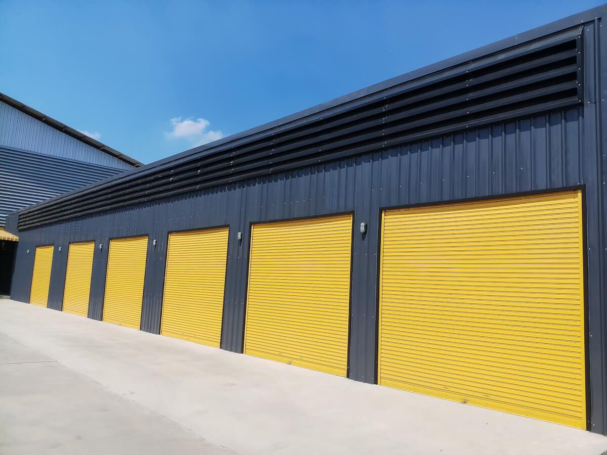 Yellow roller shutter doors on a dark-clad industrial building