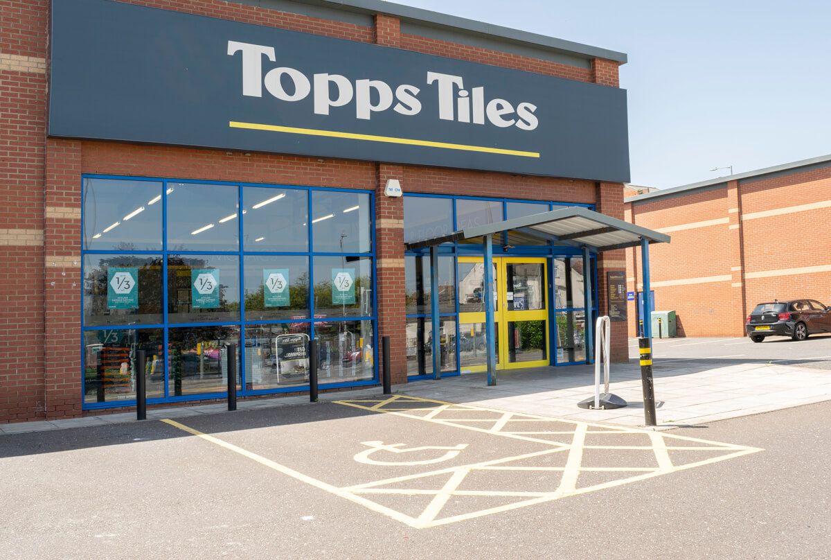 Blue aluminium shopfront glazing and yellow entrance doors at a Topps Tiles store