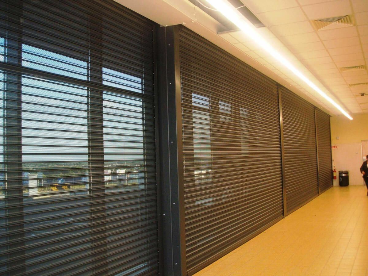 Perforated vision roller shutters closed along an internal shopping-centre mall